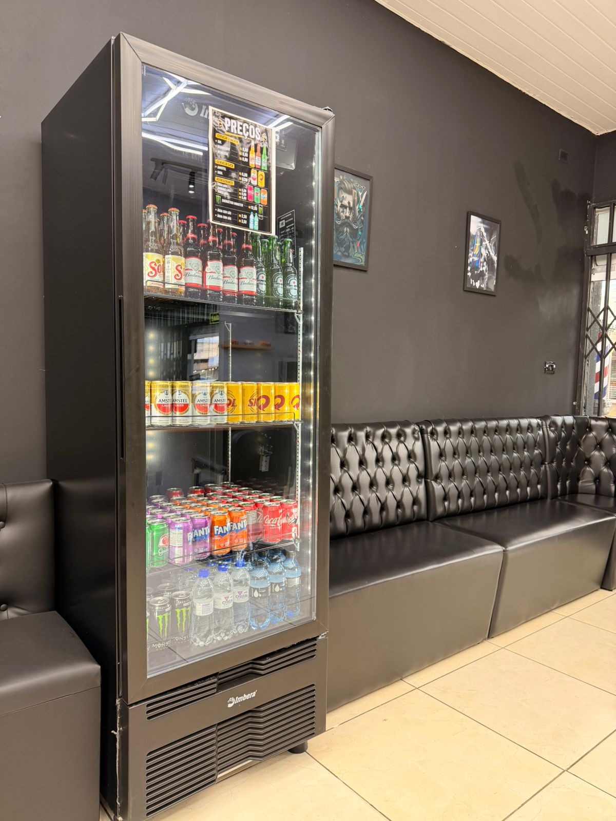 Sala de espera com sofá de couro e geladeira de bebidas